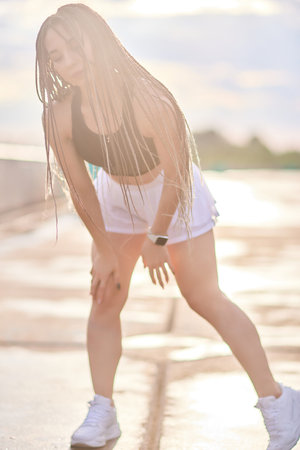 Happy successful sportswoman raising arms to the sky on golden back lighting sunset summer.