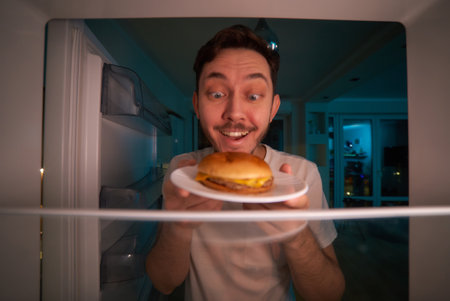 Handsome young man choosing food in refrigerator at night.の写真素材