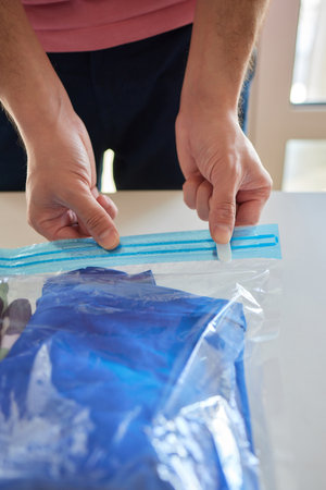 The girl pumps out air with a vacuum cleaner from a vacuum bag with clothes. The concept of storage and transportation of clothing, things. Space saving seal bag.の写真素材