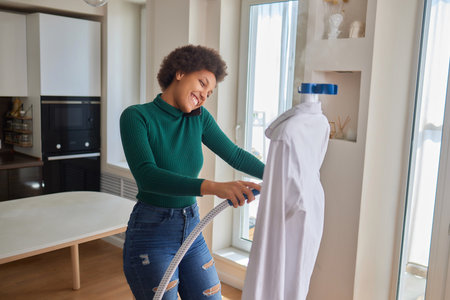 Sideways young housekeeper woman wear hold electrical streamer for dry-cleaning and ironing t-shirtの写真素材