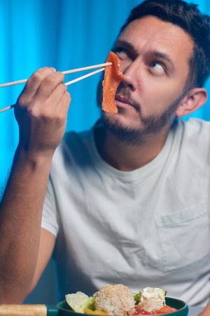 Unrecognizable man eating poke bowl with salmon,avocado,seaweedの写真素材