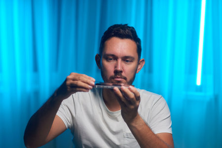 glass tempered protection film replace change mobile service. man hand uses wet wipes cloth to remove dust from black smartphone screen. new protector tempered glass top view white table.の写真素材