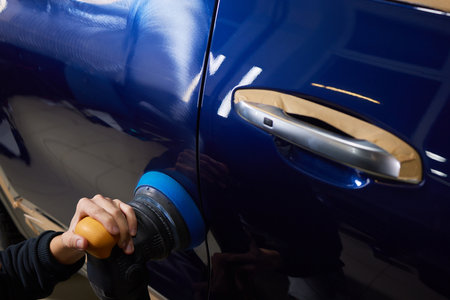 Man with an orbital polisher in car workshop polishing car closeupの写真素材