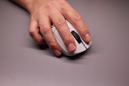 Close-up Macro Shot: Persons Hand Using Wireless Computer Mouse, Scrolls through Apps and Websites with a Wheel and Clicks on Buttonsの写真素材