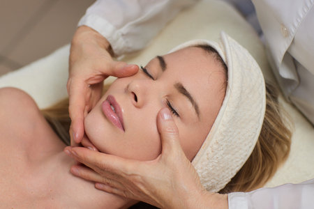 Woman receiving facial buccal massage in beauty salon.Beauty and skincare concept with a beautiful woman. Middle aged female relaxed with massage for facial liftingの写真素材