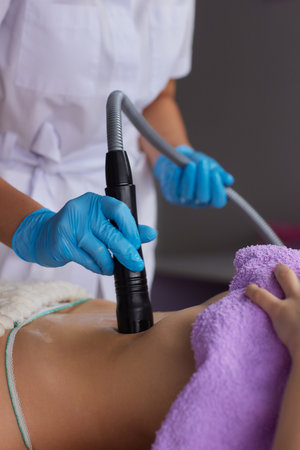 procedure removing cellulite on female abdomen, cavitation belly massage. Ultrasonic massage for weight loss. Correction of female figure without surgical intervention. Closeup of the tummyの写真素材