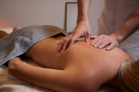 Body massage treatment. Woman having massage in the spa salon. Masseur working on his back.の写真素材