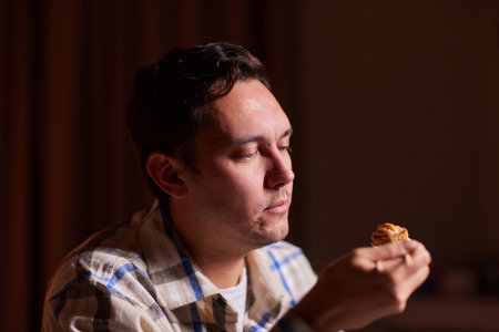 Young man eating sushi from home delivery pointing and showing with thumb up to the side with happy...