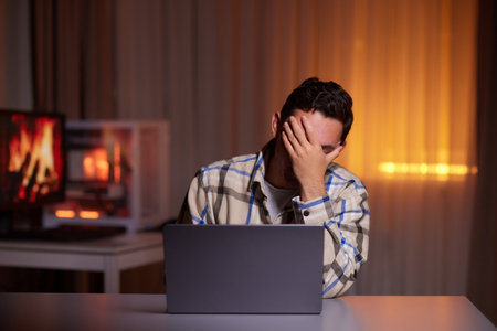 Focused young man wearing glasses using laptop, typing on keyboardの写真素材