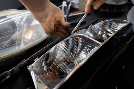 Car headlight in repair close-up. The car mechanic installs the lens in the headlight housing. The...