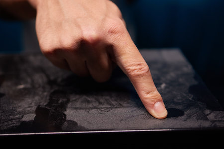caucasian hand with dust on finger tips after touching black dusty surface, closeup with selective focusの写真素材