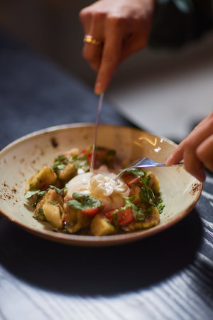 Whole tied Italian cheese burrata on small wooden plate served with fresh tomatoes and basil