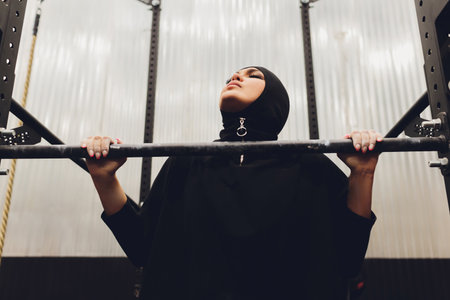 Muslim asian woman in hijab exercizing in a gym.