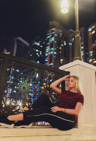 Closeup side view portrait of young sad thoughtful women leaning against street lamp at night on...