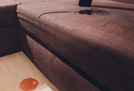 Red wine spilled on a brown couch sofa.の写真素材