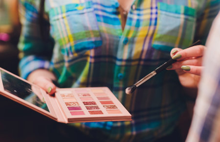 Makeup artist, beauty and people concept - Beautiful korean young woman holding palette of colorful eye shadows and brushes on white background.の写真素材