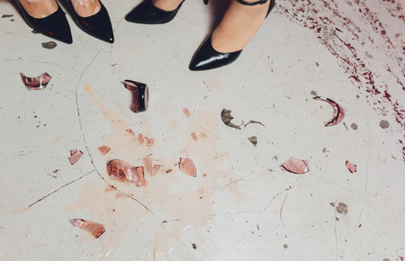 Broken wineglass on the table. Poured red wine, like blood.