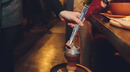 Preparation of hookah on the bar. The bartender adds mixes the contents of a transparent hookah...