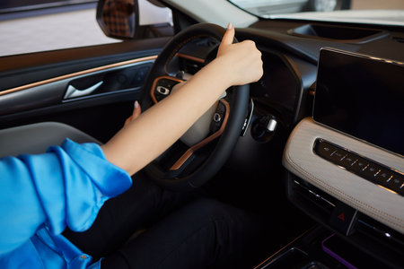 Hand of woman holding steering wheel of car
