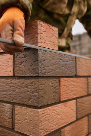 professional construction worker laying bricks and building barbecue in industrial site. Detail of...