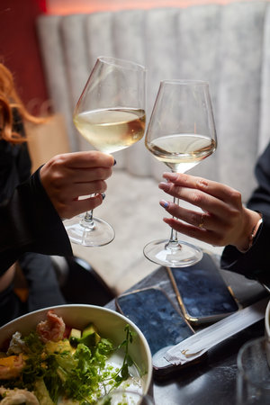 A woman holds a cocktail in her hand, with her fingers wrapped around the glass