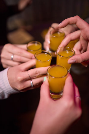 Group cheers with shot glasses of Paulaner hefeweizen wheat beer at fun event