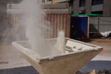 Dust is billowing up at a construction site where workers are busy with industrial cement tasksの写真素材