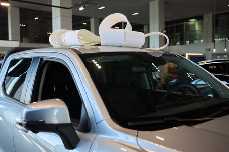 An iconic new car is being presented with a ribbon bow at the showroom for a celebratory event