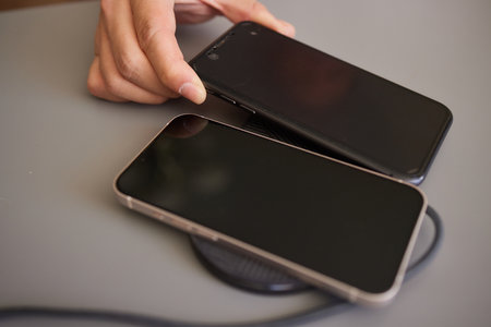Man Charging Smartphone Using Wireless Charging Pad At Homeの写真素材