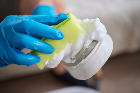 Applying cleaning foam from the bottle to white leather womens sneakers. Care for leather shoes, surface whitening.の写真素材