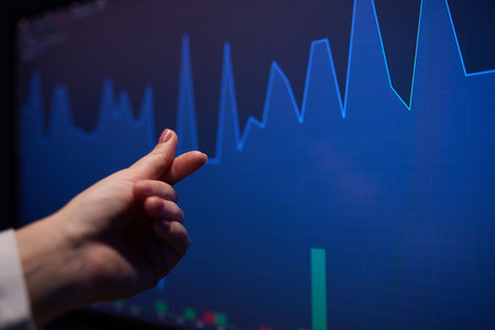 Finger to the graph on the monitor. Team of stockbrokers are having a conversation in a office with...