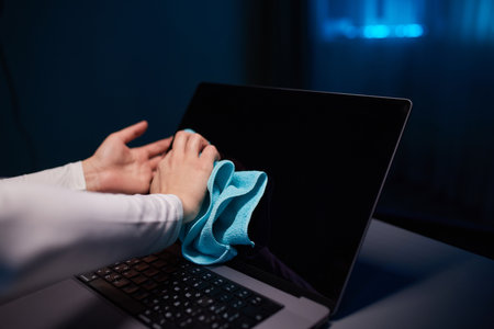 Cleaning the screen of laptop computer with microfiber cloth by hand