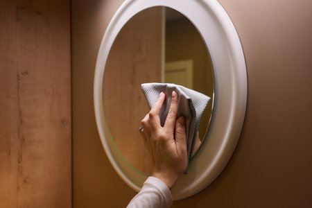 Using a cloth, Jaw cleans the mirror on the shelf