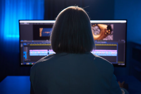 Beautiful Female Video Editor Works with Footage on Her Personal Computer, She Works in Creative Office Studio.の写真素材