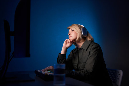 Woman with headphones at purple desk with computer monitor for entertainment