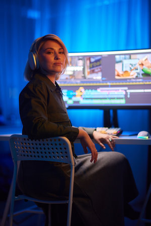 a woman wearing headphones is sitting in front of a computerの写真素材