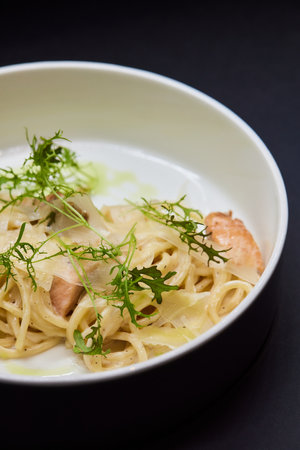 A white bowl filled with spaghetti and meat on a black backgroundの写真素材