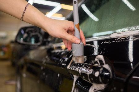 A person is cleaning a car windshield with a brush and waterの写真素材