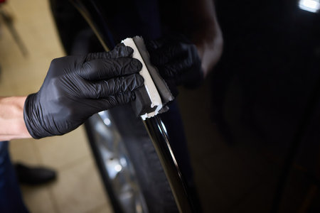 man wearing black gloves applying ceramic coating to car using sponge. Professional car detailingの写真素材
