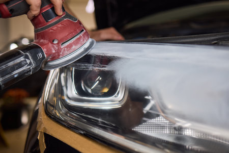 Person using a machine to polish automotive lighting on a car headlightの写真素材