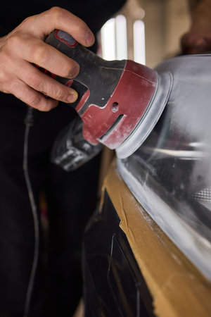 Person using a machine to polish automotive lighting on a car headlight