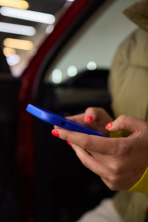 A woman shows an electric blue cell phone with red nails, in a stylish gesture