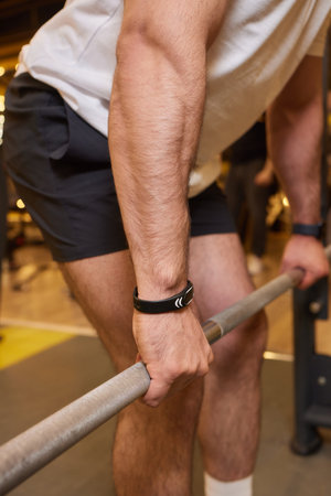 A man is strengthening and improving his fitness by lifting a barbell in the gym