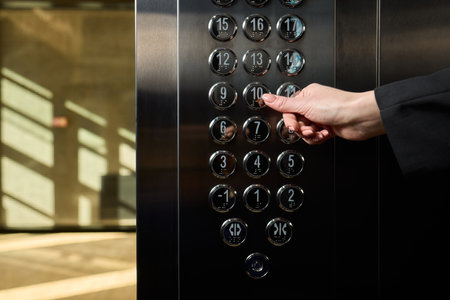 A businessman confidently stands in an elevator while pressing a button to reach his desired floor