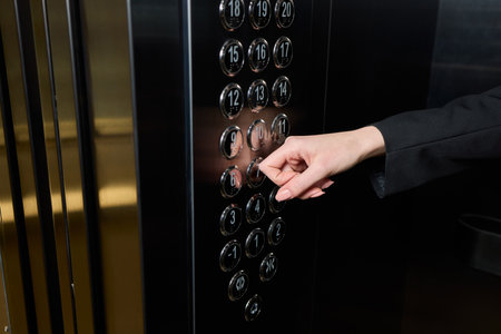 A businessman confidently stands in an elevator while pressing a button to reach his desired floor