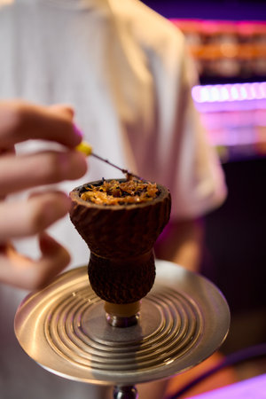 Close up of a hookah made of metal and glass on a wooden table