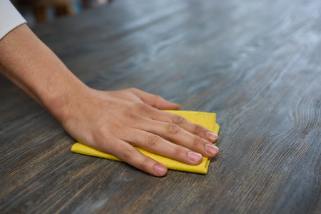 A person is grasping a yellow napkin in their hand while standing