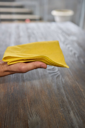 A person is grasping a yellow napkin in their hand while standingの写真素材