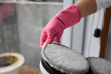 A robotic white Automotive tire is cleaning a glass window replacing cleaning cloths