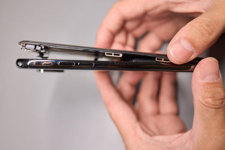 A person halves a broken cell phone, revealing its internal componentsの写真素材